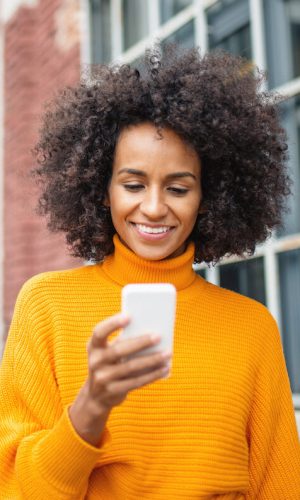 Smiling African American woman using mobile phone outdoor